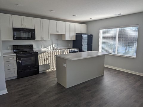 a kitchen with white cabinets and black appliances and a white counter top